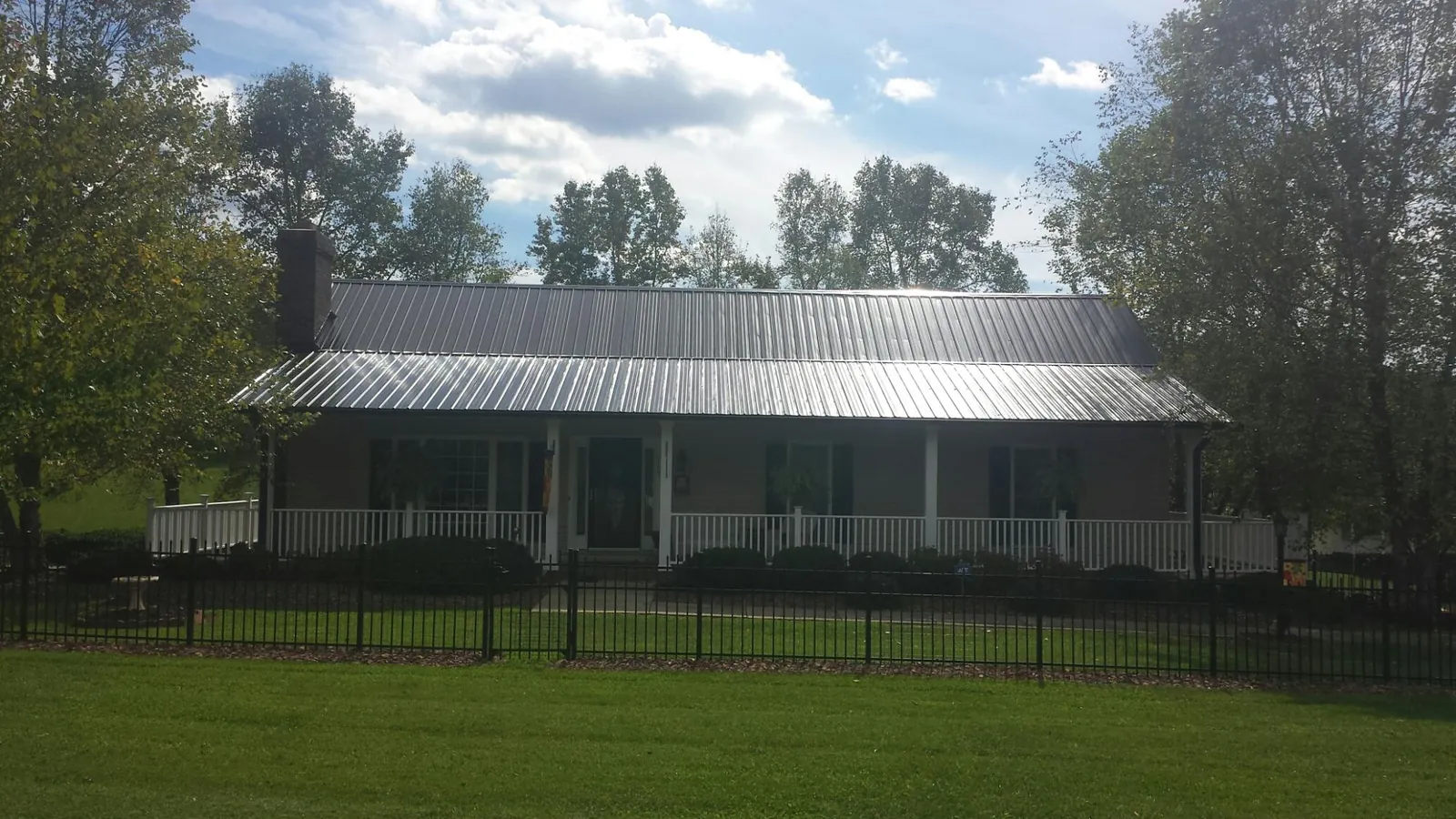 Gray metal roof on a brick ranch with a full width front porch — Gutter Guard Installation work by our crew in Summerfield